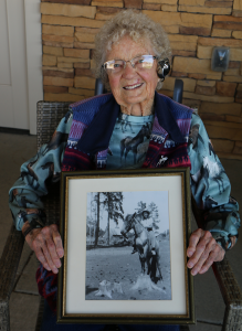 Vera Montgomery holding a photo of herself when she was 13 on horseback at her family’s farm
